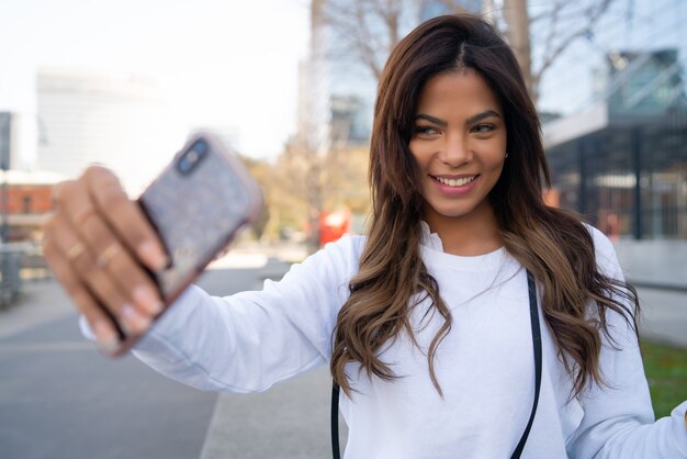 Retrato de uma jovem tirando selfies com seu telefone móvel ao ar livre
