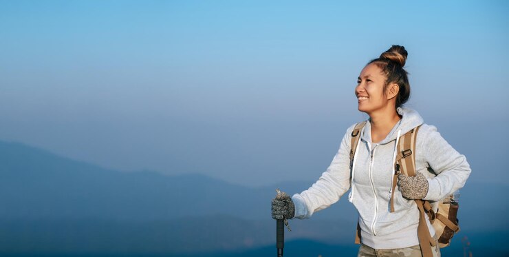 Foto grátis retrato de uma jovem turista asiática está caminhando no topo da montagem e olhando para uma bela paisagem com espaço de cópia viagem estilo de vida aventura conceito de aventura férias ao ar livre