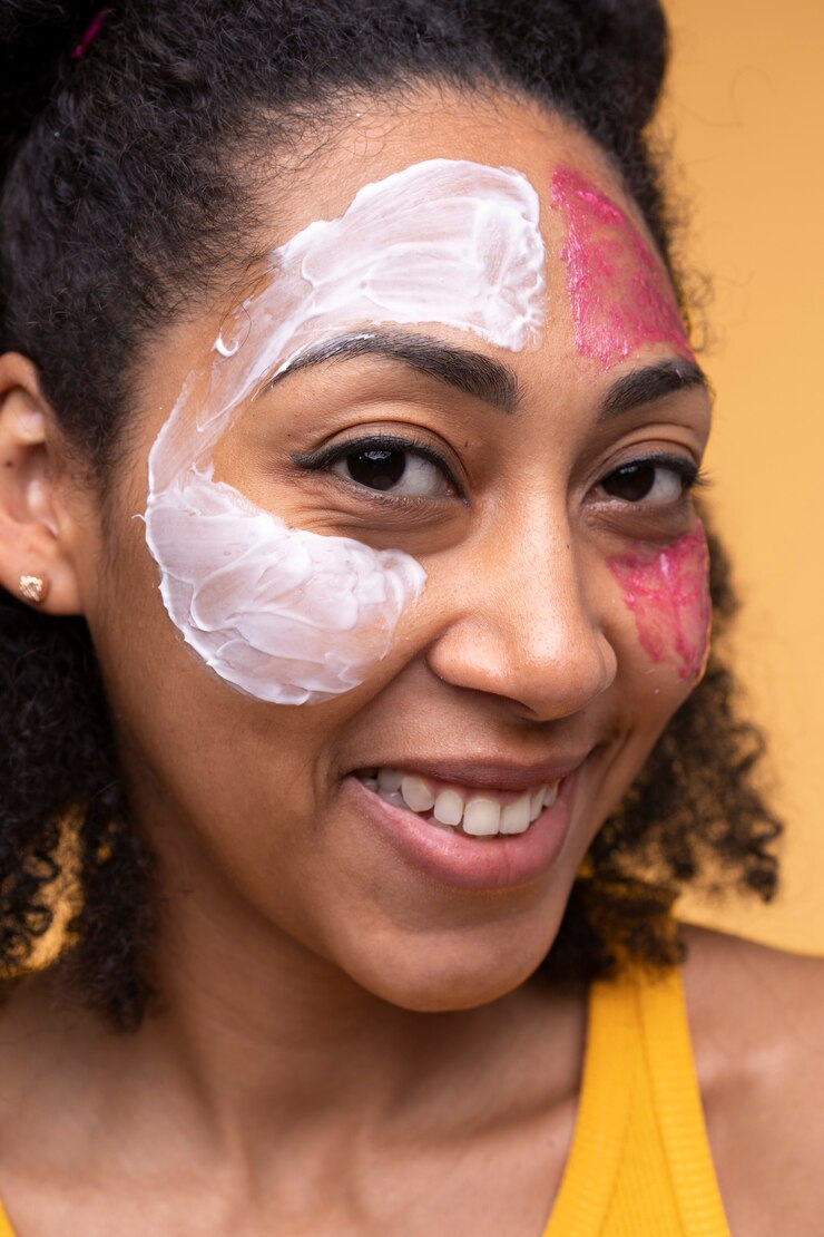 Foto grátis retrato de uma jovem usando hidratante e máscara facial