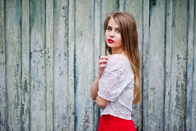 Retrato de uma linda garota com lábios vermelhos contra fundo de madeira vestindo vestido vermelho e blusa branca