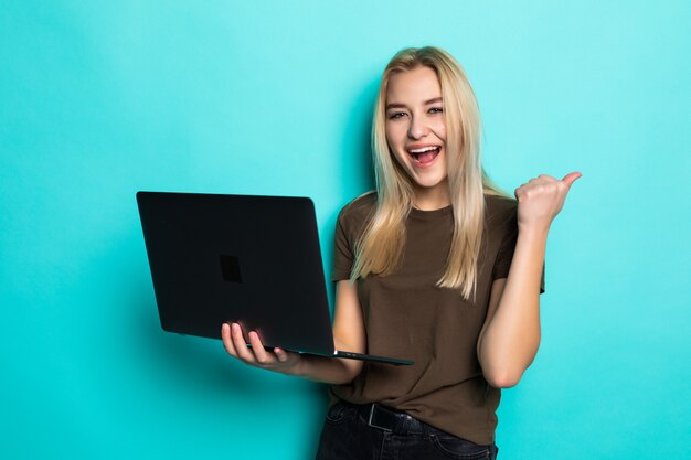 Retrato de uma linda menina bonita segurando laptop isolado sobre parede azul