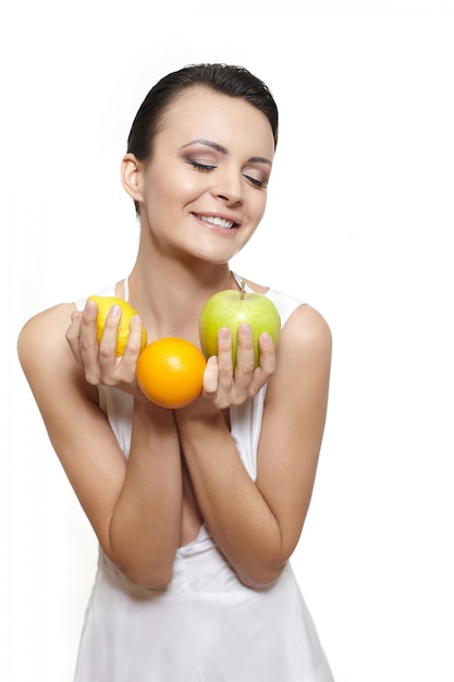 Retrato de uma linda menina sorridente feliz com frutas limão e maçã verde e laranja isolado no branco