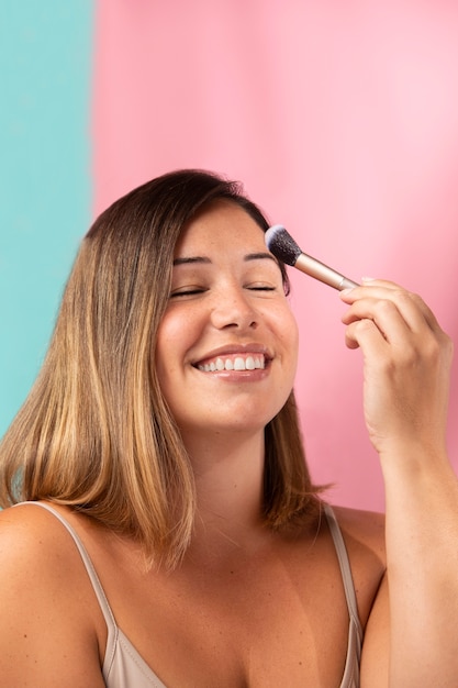 Retrato de uma linda mulher aplicando maquiagem com um pincel