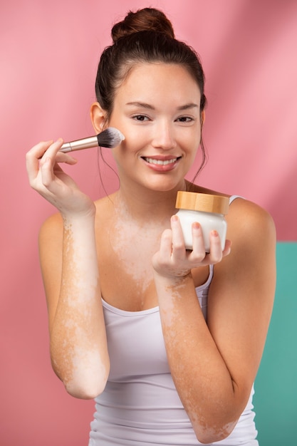 Retrato de uma linda mulher aplicando pó com um pincel de maquiagem