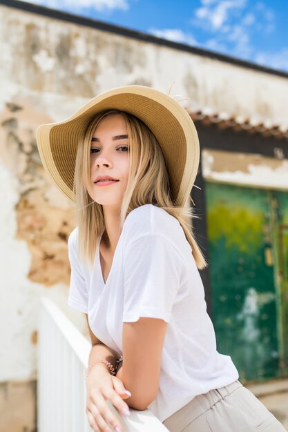 Retrato de uma linda mulher caucasiana no terraço de verão com um sorriso no chapéu de verão