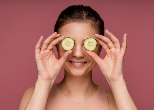 Retrato de uma linda mulher cobrindo os olhos com fatias de pepino