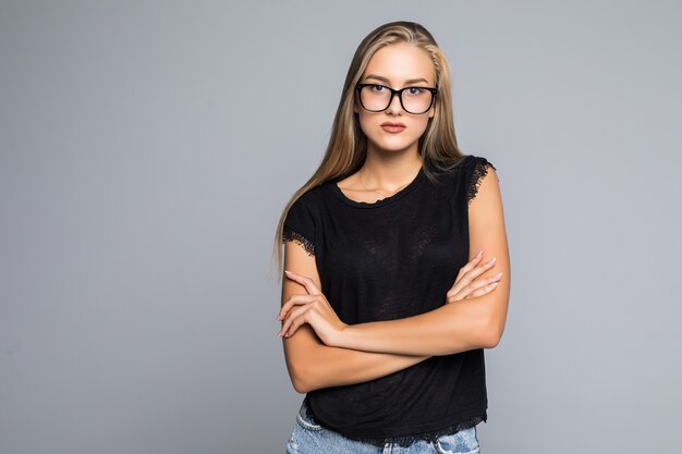 Retrato de uma linda mulher em pé com as mãos postas e olhando para a câmera sobre um fundo cinza