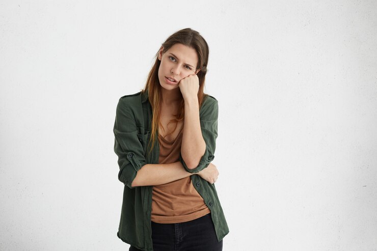 Foto grátis retrato de uma linda mulher europeia com cabelos longos, vestida com uma jaqueta verde casual, parecendo exausta, apoiada na mão dela