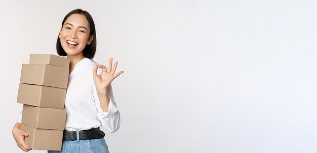 Retrato de uma linda mulher feliz carrega caixas com pedidos Empresária com entrega de transporte e mostrando fundo branco de sinal bem