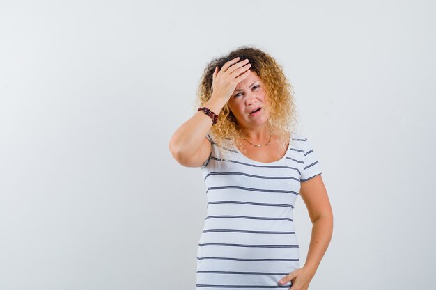 Retrato de uma linda mulher sofrendo de dor de cabeça em uma camiseta e olhando estressada de frente