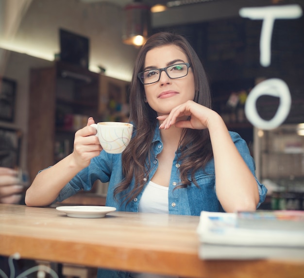 Foto grátis retrato de uma linda mulher tomando café em um café