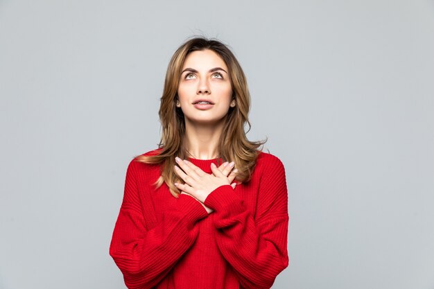 Retrato de uma linda mulher vestida de suéter vermelho isolado sobre parede cinza