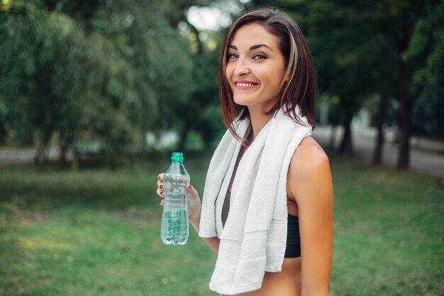 Retrato de uma menina atlética. Modelo de fitness esporte jovem bonita segurando uma garrafa de água