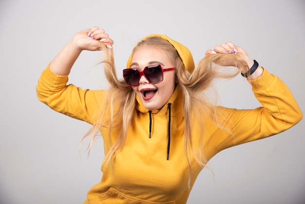 Retrato de uma menina bonita com capuz amarelo de óculos elegantes.