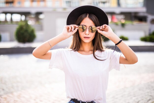 Retrato de uma menina bonita em óculos de sol e chapéu ioutdoors