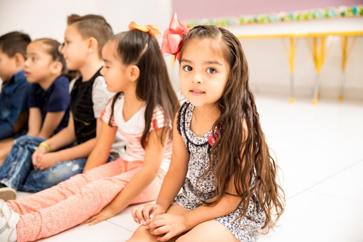 Foto grátis retrato de uma menina bonita sentada no chão durante a aula e fazendo contato visual