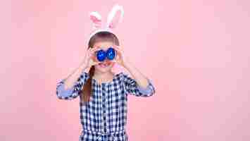 Foto grátis retrato de uma menina bonitinha com ovos de páscoa em um fundo rosa.
