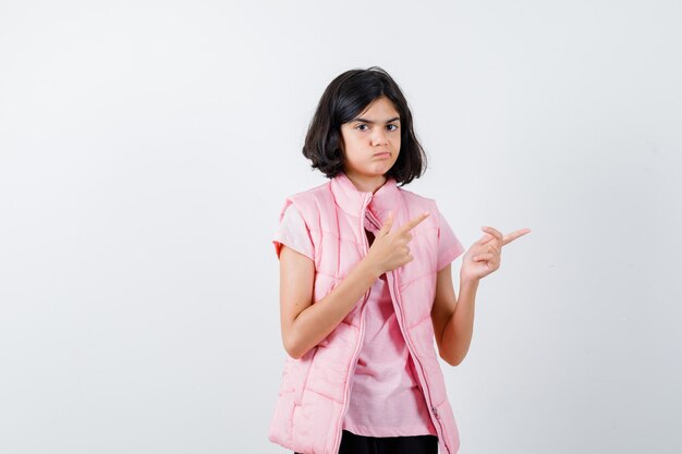 Retrato de uma menina com camiseta branca e colete bufê apontando