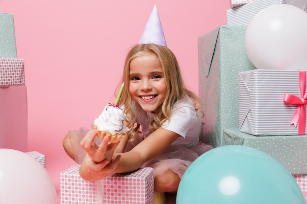 Retrato de uma menina em um chapéu de aniversário comemorando