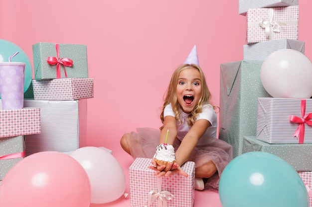 Retrato de uma menina em um chapéu de aniversário comemorando