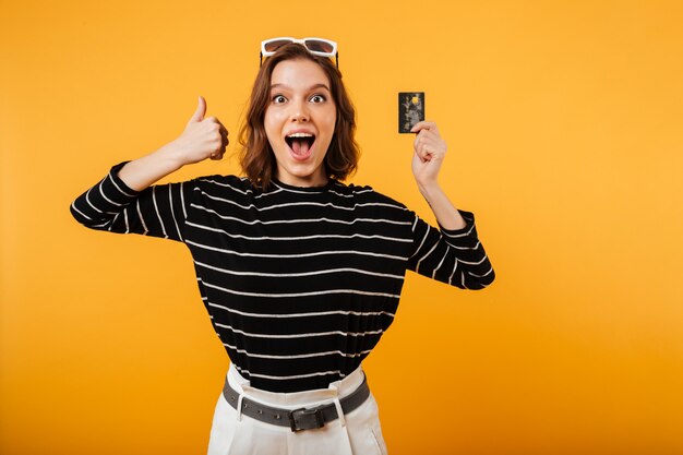 Retrato de uma menina feliz, segurando o cartão de crédito