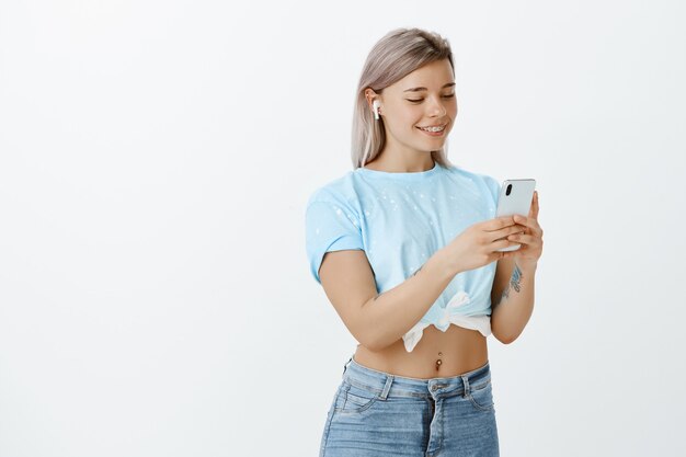 Retrato de uma menina loira bonita posando no estúdio com seu telefone e fones de ouvido