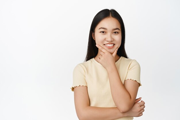 Retrato de uma menina pensativa sorridente, parecendo satisfeita e pensando em ouvir uma sugestão interessante, uma ideia de fundo branco