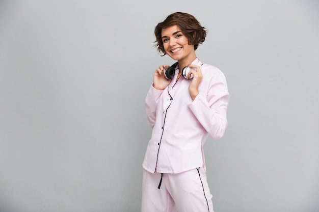 Retrato de uma menina sorridente alegre de pijama com fones de ouvido