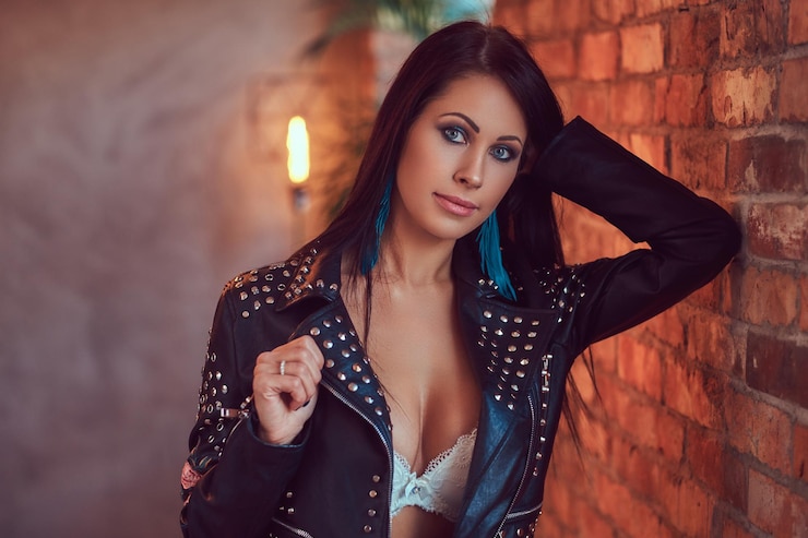 Foto grátis retrato de uma morena sensual sexy posando de cueca e elegante jaqueta de couro encostada em uma parede de tijolos.