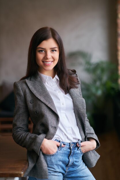 Retrato de uma morena sexy encostada em uma mesa em uma sala com lo