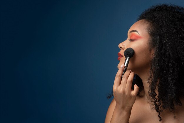 Retrato de uma mulher aplicando maquiagem com um pincel de maquiagem