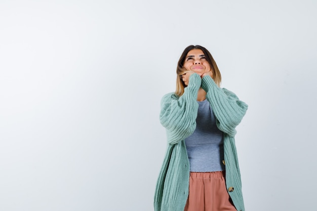 Retrato de uma mulher apoiando o rosto nas mãos em roupas casuais e olhando para a frente