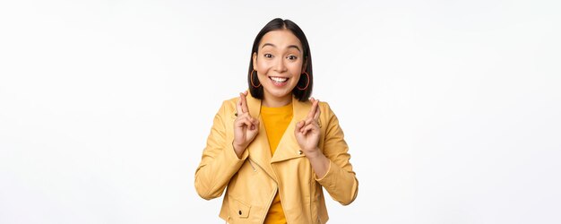 Retrato de uma mulher asiática animada parece esperançosa desejando orar ou implorar esperando por notícias em pé o