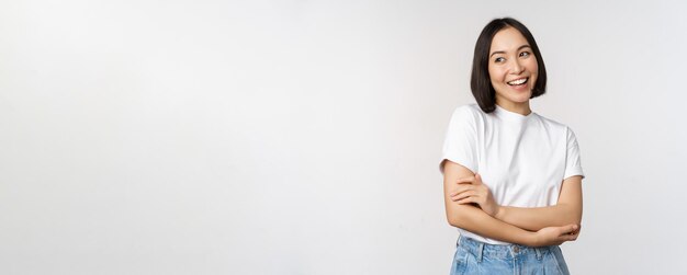 Retrato de uma mulher asiática feliz sorrindo posando confiantes braços cruzados no peito em pé contra o estúdio b