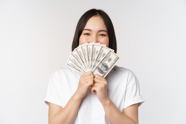 Retrato de uma mulher asiática sorridente segurando o conceito de dinheiro em dólares de finanças de microcrédito e dinheiro em pé sobre fundo branco