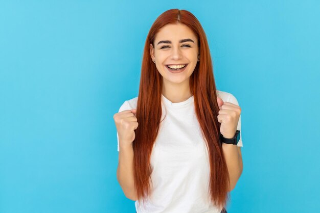 Retrato de uma mulher atraente, alegre e sortuda comemorando o sucesso isolado em um azul vibrante