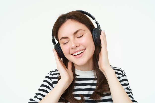 Foto grátis retrato de uma mulher bonita com fones de ouvido sem fio ouvindo música usando fones de ouvir sorrindo para a câmera