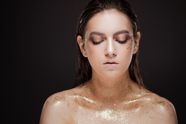 Retrato de uma mulher bonita com maquiagem criativa de ouro