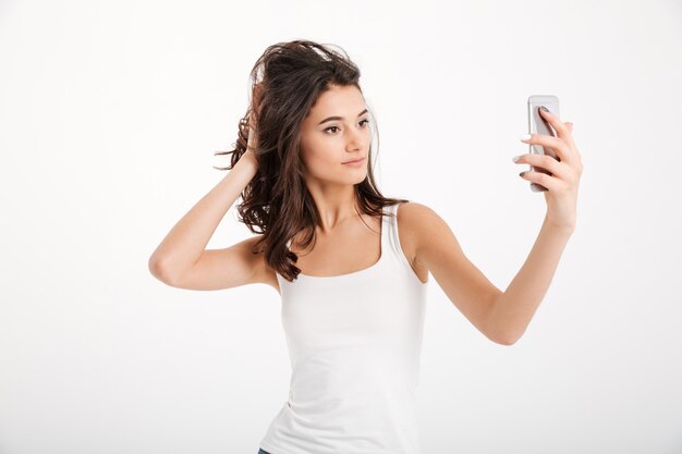 Retrato de uma mulher bonita, vestida com uma blusa, tomando uma selfie