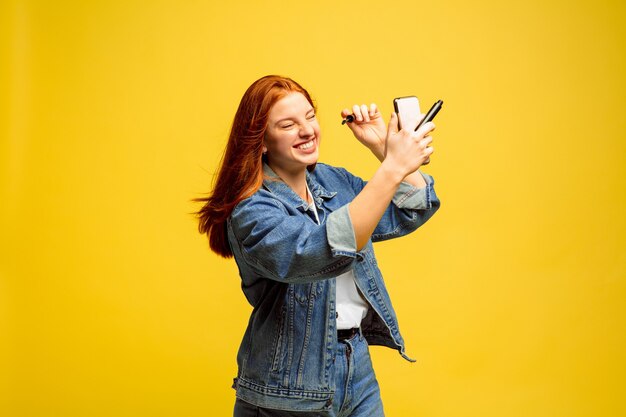 Retrato de uma mulher caucasiana em fundo amarelo. Modelo de cabelo vermelho feminino lindo. Conceito de emoções humanas, expressão facial