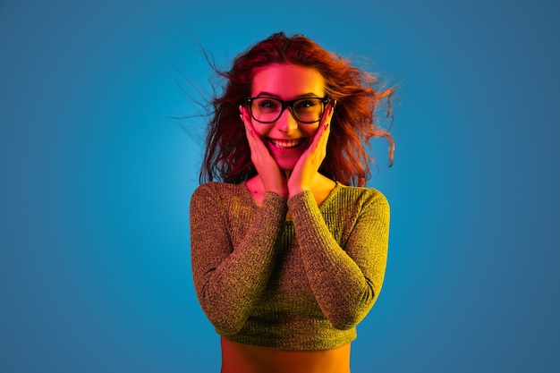 Foto grátis retrato de uma mulher caucasiana isolado no fundo azul do estúdio em luz de néon