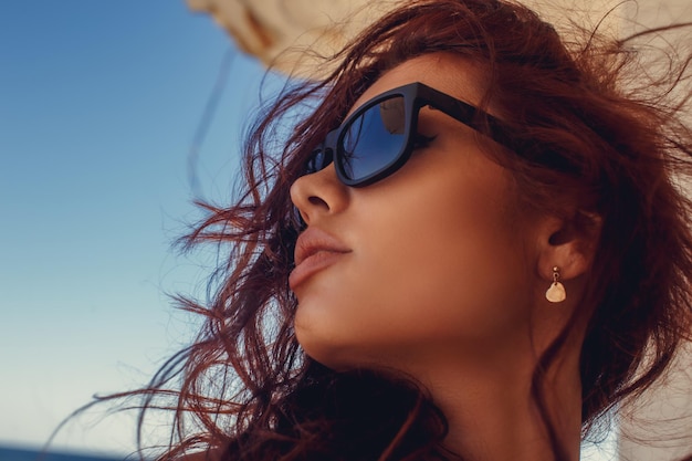 Retrato de uma mulher com cabelo vermelho em óculos de sol.