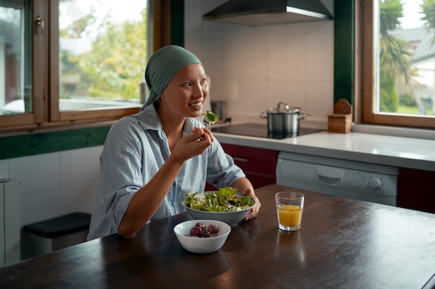Retrato de uma mulher com câncer comendo salada em casa