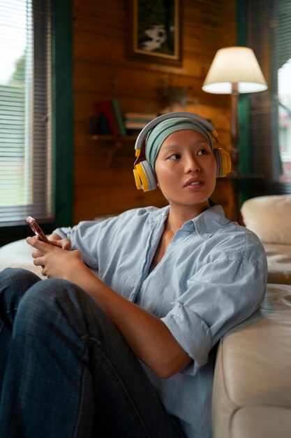 Foto grátis retrato de uma mulher com câncer ouvindo música em casa