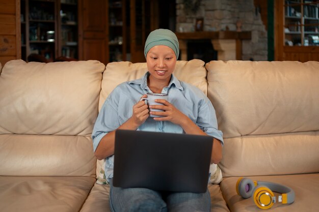 Retrato de uma mulher com câncer usando seu laptop em casa