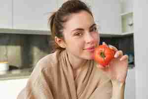 Foto grátis retrato de uma mulher cozinhando em casa na cozinha segurando tomates preparando uma deliciosa refeição fresca