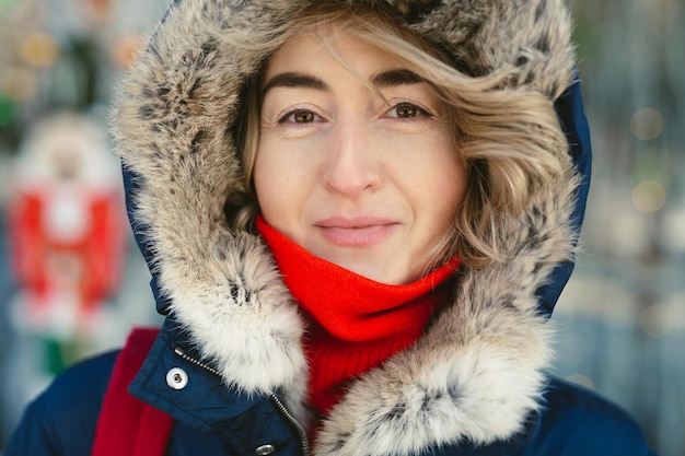 Retrato de uma mulher de capuz e um lenço vermelho em um dia gelado.