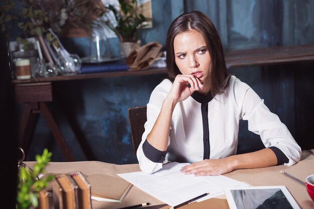 Retrato de uma mulher de negócios que está trabalhando no escritório e verificando detalhes de sua próxima reunião em seu caderno e trabalhando no loft.