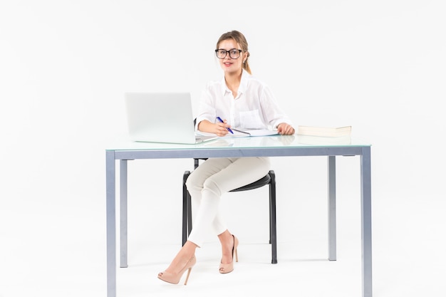 Retrato de uma mulher de negócios sentado em uma mesa com um laptop isolado no fundo branco