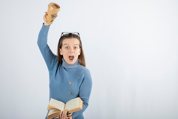 Retrato de uma mulher de óculos, segurando um livro e uma xícara de café.